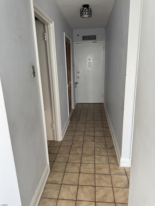 hallway featuring light tile patterned floors, visible vents, and baseboards