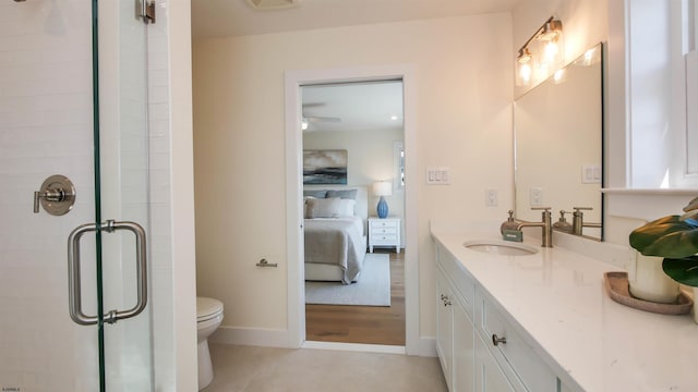 ensuite bathroom with baseboards, toilet, a stall shower, ensuite bathroom, and vanity