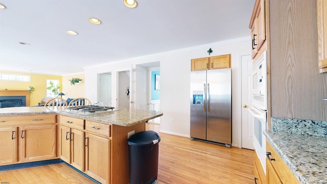 kitchen with light wood finished floors, crown molding, and stainless steel fridge with ice dispenser