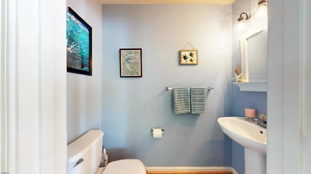 half bathroom with a sink, baseboards, and toilet