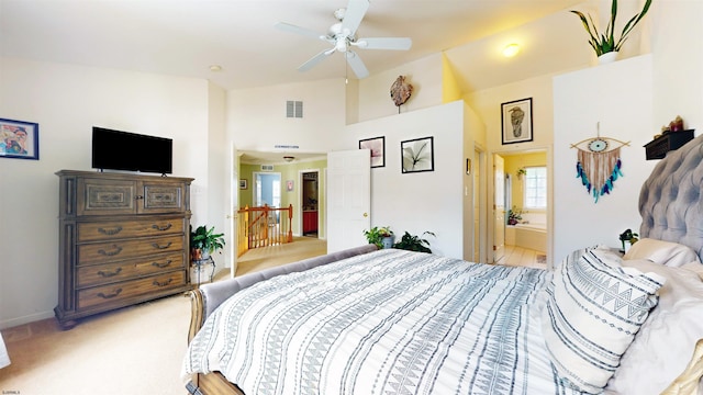 bedroom featuring visible vents, high vaulted ceiling, ceiling fan, ensuite bathroom, and light colored carpet