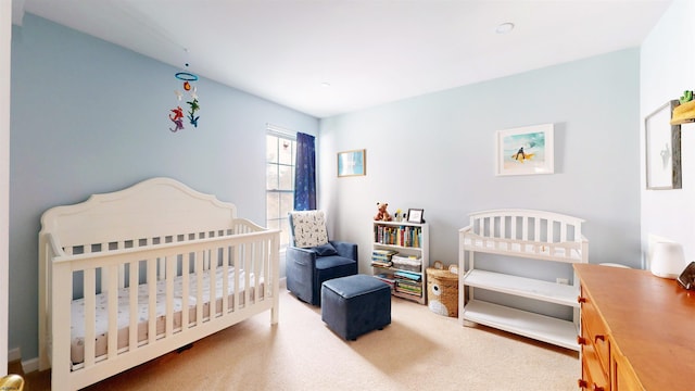 bedroom featuring a nursery area and carpet floors