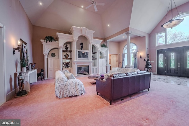 living room featuring decorative columns, high vaulted ceiling, a glass covered fireplace, and carpet flooring