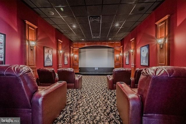 carpeted home theater featuring arched walkways and a drop ceiling