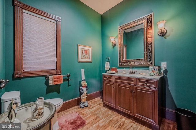 bathroom with vanity, toilet, wood finished floors, and baseboards