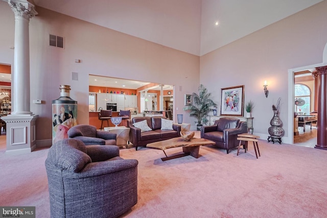 living area with light carpet, visible vents, baseboards, and decorative columns