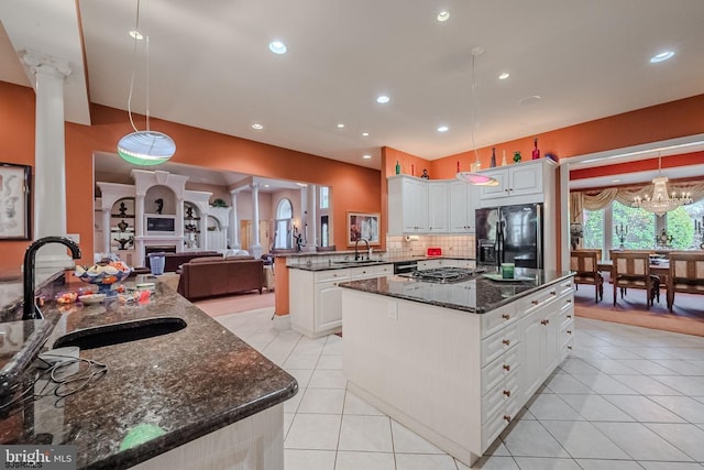 kitchen with a sink, a center island, light tile patterned flooring, a fireplace, and black refrigerator with ice dispenser