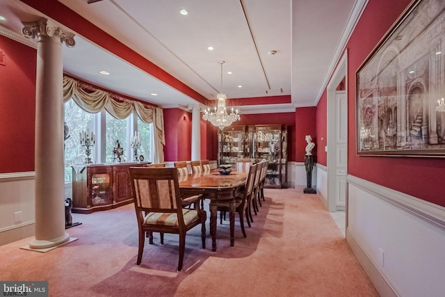 dining room with a tray ceiling, a wainscoted wall, light carpet, and ornate columns