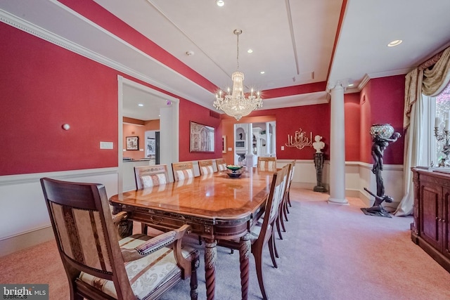 dining space with light colored carpet, a tray ceiling, ornamental molding, and decorative columns