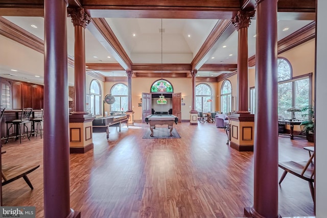 living area with wood finished floors, decorative columns, ornamental molding, pool table, and a towering ceiling