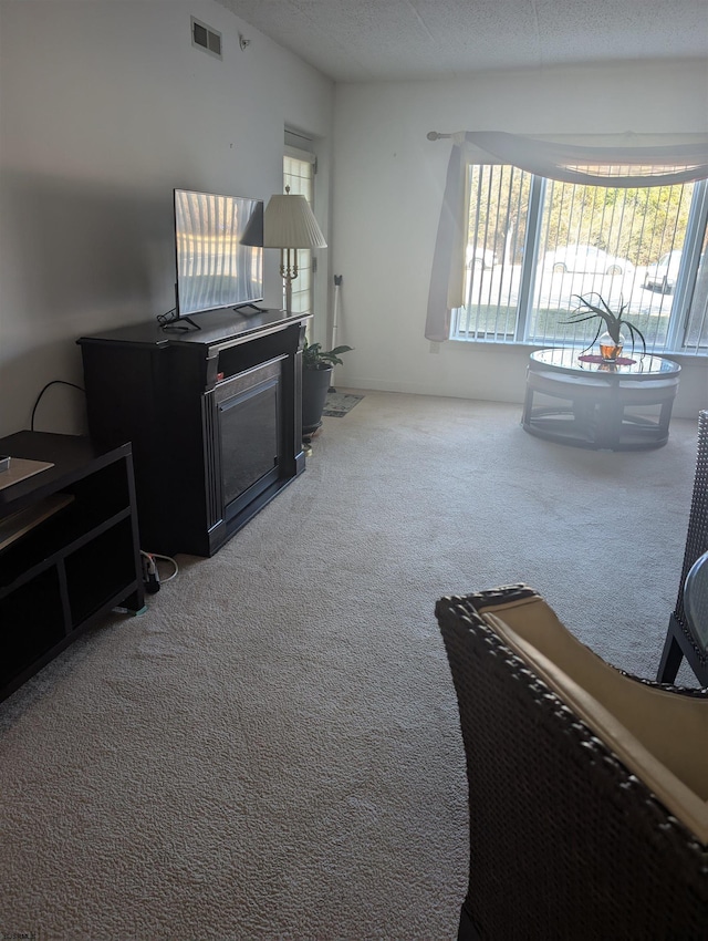 living room featuring carpet flooring, visible vents, and a textured ceiling