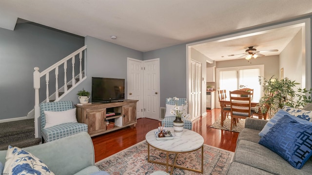 living room with baseboards, a ceiling fan, wood finished floors, and stairs