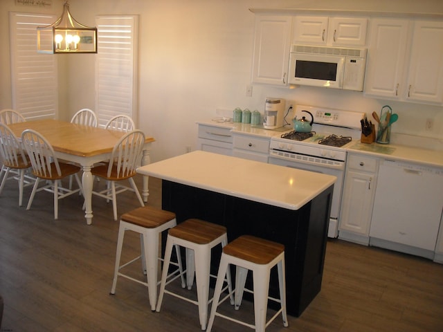 kitchen with a kitchen breakfast bar, white appliances, white cabinets, and dark wood-style flooring