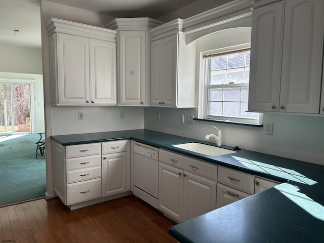 kitchen with dark wood-type flooring, a sink, dark countertops, white cabinets, and white dishwasher