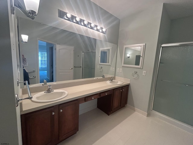 bathroom with double vanity, a stall shower, baseboards, and a sink