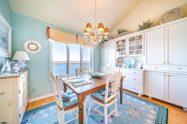 dining room with baseboards, a water view, lofted ceiling, light wood-style flooring, and a notable chandelier