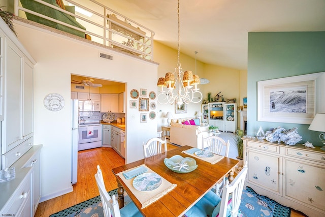 dining area featuring visible vents, high vaulted ceiling, light wood-style flooring, and a chandelier