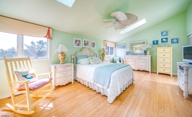 bedroom featuring vaulted ceiling with skylight, ceiling fan, and hardwood / wood-style flooring