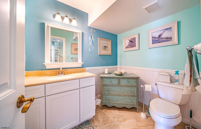 bathroom featuring tile patterned floors, visible vents, a wainscoted wall, toilet, and vanity