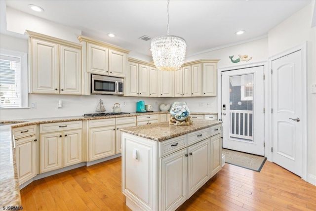 kitchen featuring hanging light fixtures, cream cabinets, light wood-style floors, and stainless steel appliances