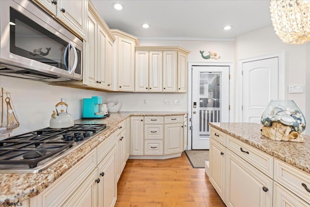 kitchen with light stone countertops, recessed lighting, cream cabinetry, light wood-style floors, and appliances with stainless steel finishes