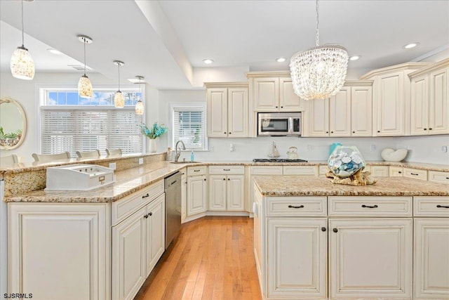 kitchen featuring a sink, stainless steel appliances, light wood-type flooring, and light stone countertops