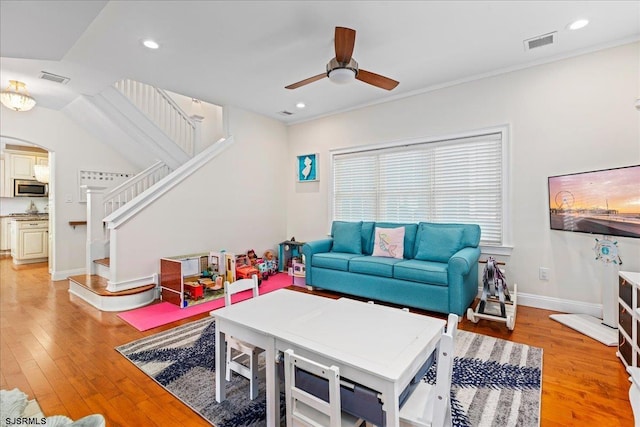 living area with arched walkways, visible vents, light wood-style flooring, and stairway