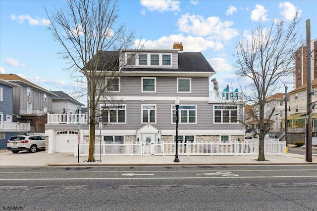 view of front facade featuring a fenced front yard, a garage, concrete driveway, and a chimney