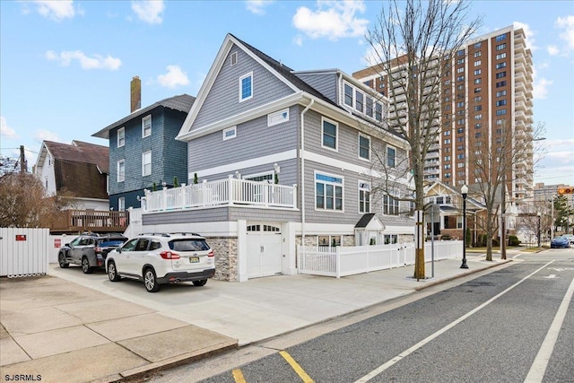 view of front of house featuring stone siding, concrete driveway, a garage, and fence