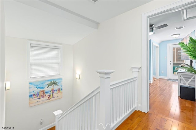 hallway with visible vents, an upstairs landing, wood-type flooring, wainscoting, and vaulted ceiling