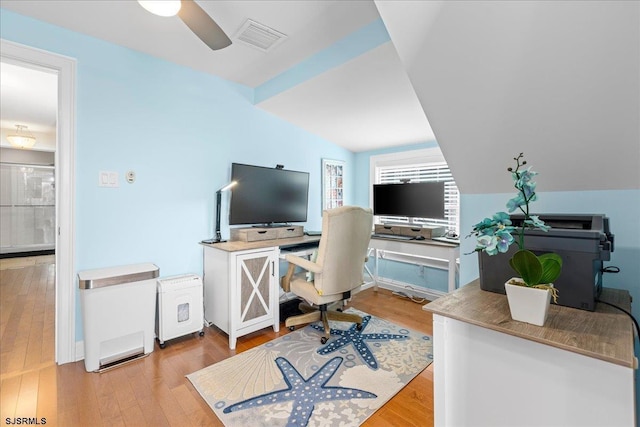 office area featuring vaulted ceiling, visible vents, light wood finished floors, and ceiling fan