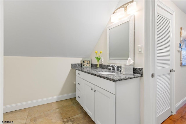 bathroom with vanity, baseboards, and vaulted ceiling