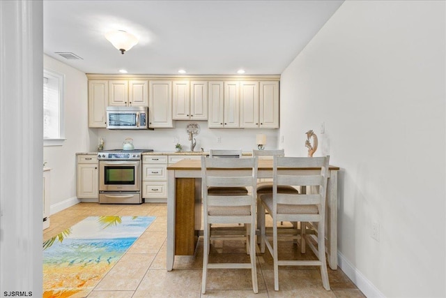 kitchen with visible vents, light countertops, light tile patterned floors, appliances with stainless steel finishes, and cream cabinets