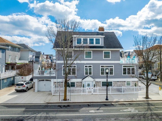 view of front of home featuring a fenced front yard, a residential view, a chimney, and stone siding