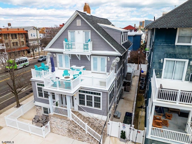 back of property featuring a chimney, a balcony, a fenced backyard, a patio area, and a gate