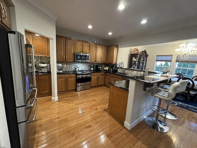 kitchen with stainless steel appliances, a peninsula, a breakfast bar area, and brown cabinetry