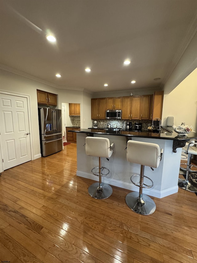 kitchen with stainless steel appliances, brown cabinets, a peninsula, and hardwood / wood-style flooring