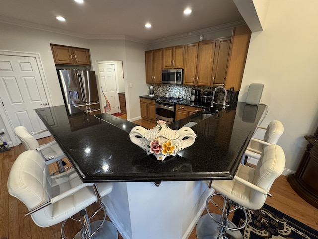 kitchen featuring tasteful backsplash, brown cabinets, appliances with stainless steel finishes, and a peninsula