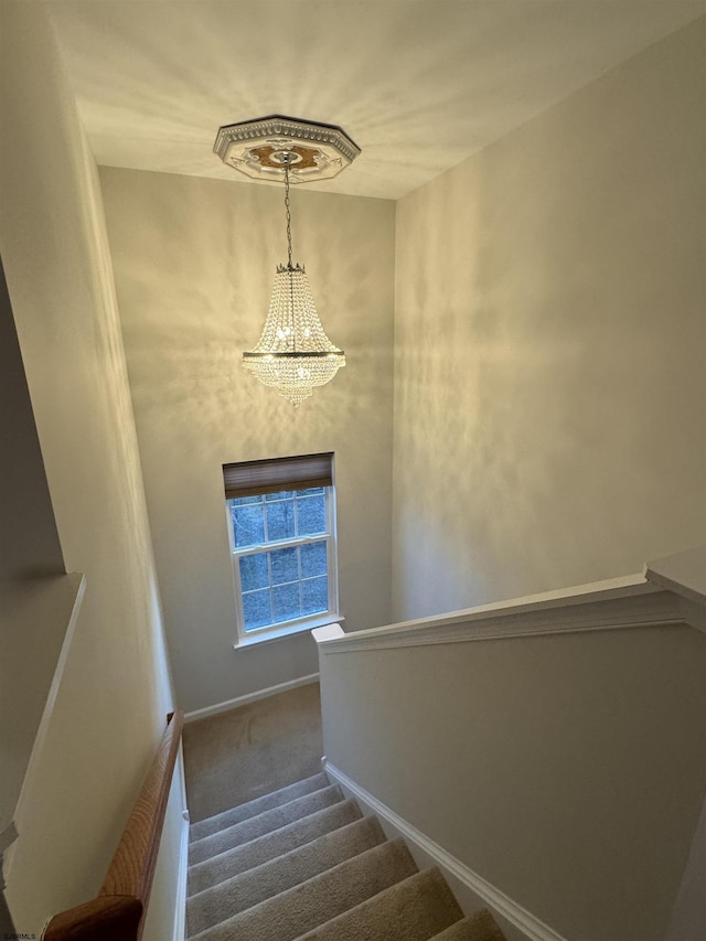 staircase featuring a notable chandelier, baseboards, and carpet floors