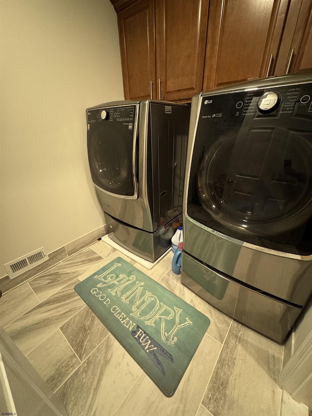 laundry room featuring visible vents, cabinet space, baseboards, and washing machine and clothes dryer