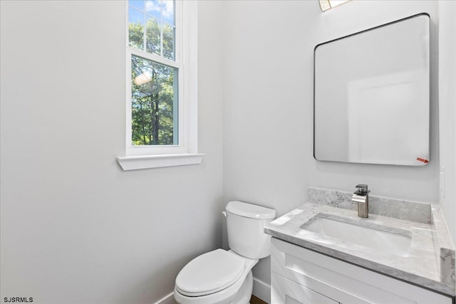 bathroom with vanity, toilet, baseboards, and a wealth of natural light