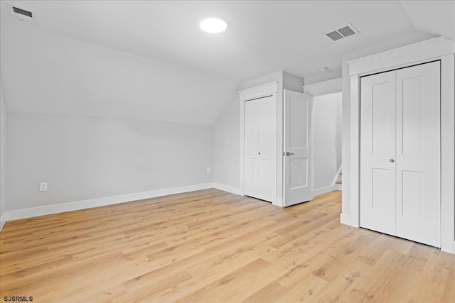 additional living space featuring light wood-type flooring, visible vents, baseboards, and vaulted ceiling