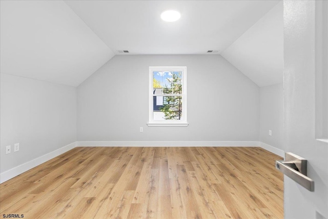 additional living space featuring light wood-style flooring, baseboards, and vaulted ceiling