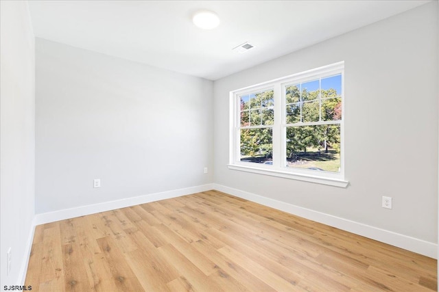 empty room featuring visible vents, light wood-type flooring, and baseboards