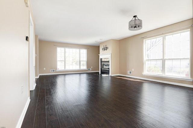 unfurnished living room with a tile fireplace, baseboards, and dark wood-style flooring