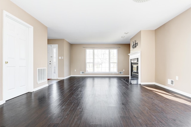 unfurnished living room featuring dark wood-type flooring, baseboards, visible vents, and a tile fireplace