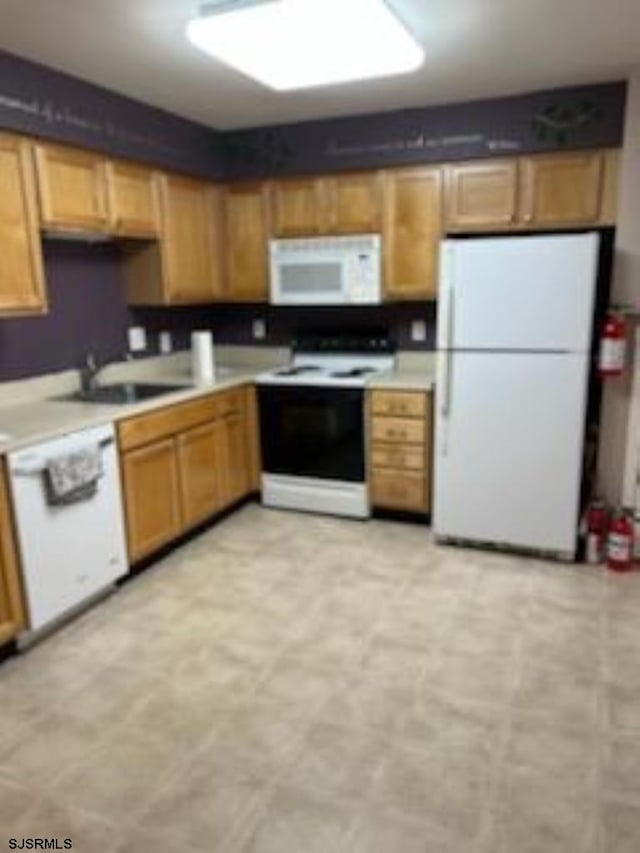 kitchen featuring white appliances, light countertops, light floors, and a sink