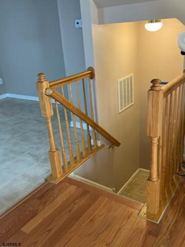 stairway featuring visible vents, baseboards, and wood finished floors