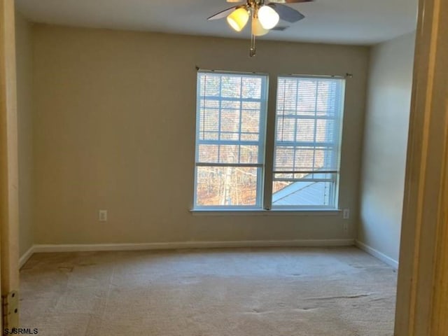 empty room featuring a wealth of natural light, baseboards, and light carpet