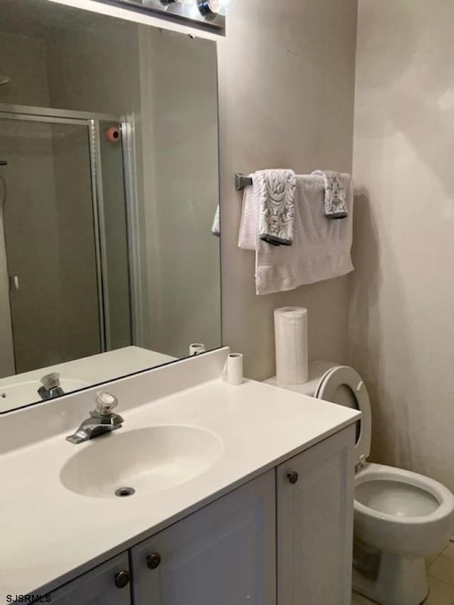 bathroom featuring toilet, a stall shower, vanity, and tile patterned flooring